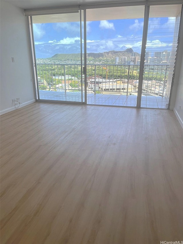 2439 Kapiolani Blvd Unit 1802, Honolulu, HI 96826 - unfurnished room with a mountain view, baseboards, wood finished floors, and a wall of windows