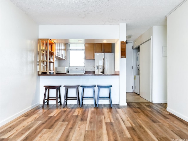 98-099 Uao Pl Unit 3209, Aiea, HI 96701 - kitchen featuring stainless steel refrigerator with ice dispenser, white microwave, a kitchen breakfast bar, wood finished floors, and a textured ceiling
