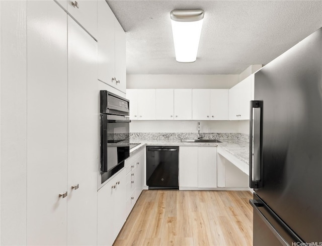 1717 Ala Wai Blvd Unit 701, Honolulu, HI 96815 - kitchen featuring black appliances, a sink, light wood-style floors, a textured ceiling, and white cabinetry