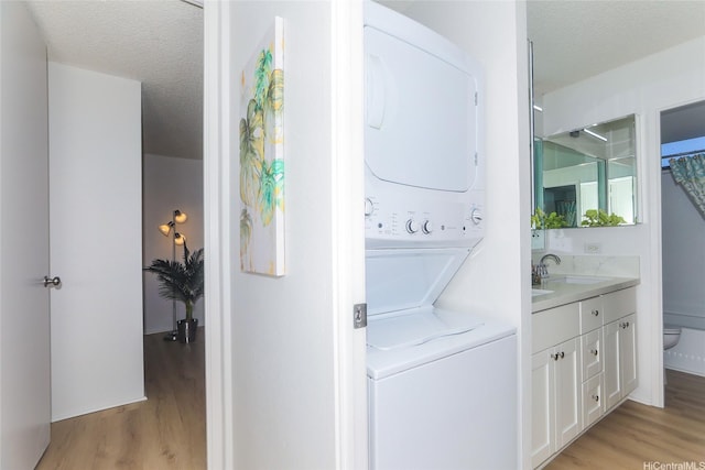 98-500 Koauka Loop Unit 23H, Aiea, HI 96701 - laundry room featuring estacked washer and dryer, light wood finished floors, and a textured ceiling
