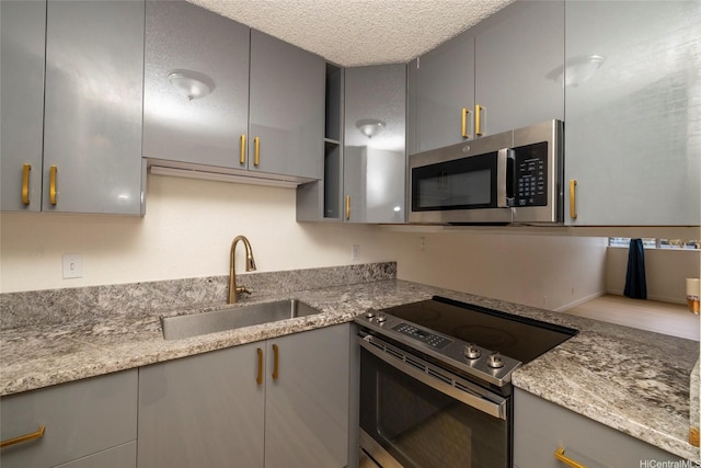 46-232 Kahuhipa St Unit B205, Kaneohe, HI 96744 - kitchen featuring stainless steel appliances, gray cabinetry, a sink, a textured ceiling, and light stone countertops