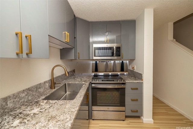 46-232 Kahuhipa St Unit B205, Kaneohe, HI 96744 - kitchen with appliances with stainless steel finishes, gray cabinetry, a sink, light wood-type flooring, and light stone countertops