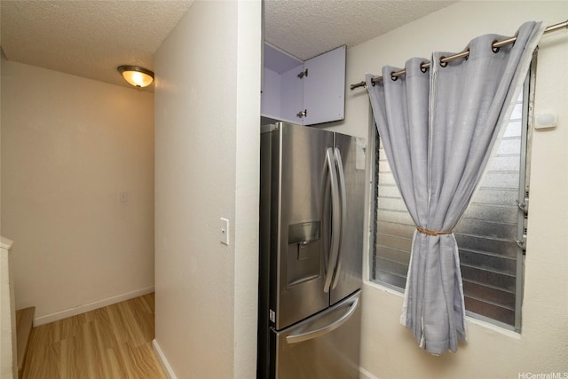 46-232 Kahuhipa St Unit B205, Kaneohe, HI 96744 - kitchen featuring stainless steel fridge with ice dispenser, light wood finished floors, a textured ceiling, baseboards, and white cabinets