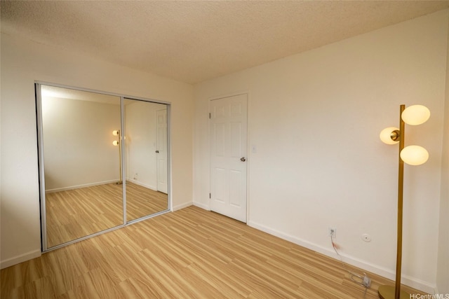 46-232 Kahuhipa St Unit B205, Kaneohe, HI 96744 - unfurnished bedroom with light wood-style flooring, baseboards, a closet, and a textured ceiling