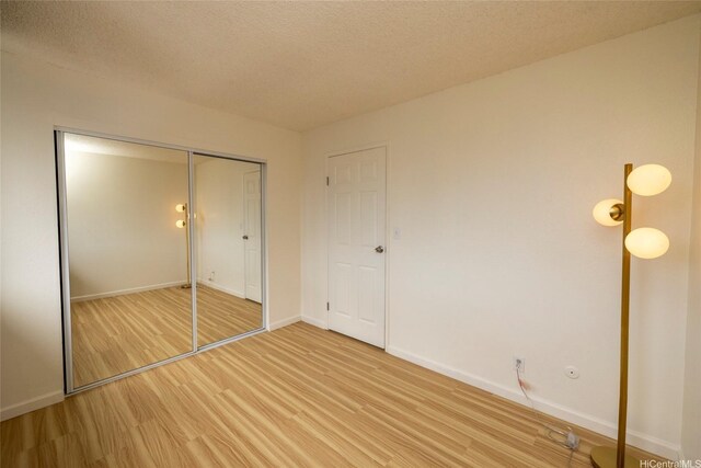 46-232 Kahuhipa St Unit B205, Kaneohe, HI 96744 - unfurnished bedroom with light wood-type flooring, a closet, and a textured ceiling