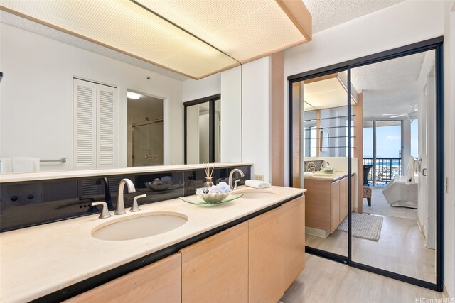 1212 Nuuanu Ave Unit 2509, Honolulu, HI 96817 - full bathroom featuring wood finished floors, double vanity, a shower with door, and a closet