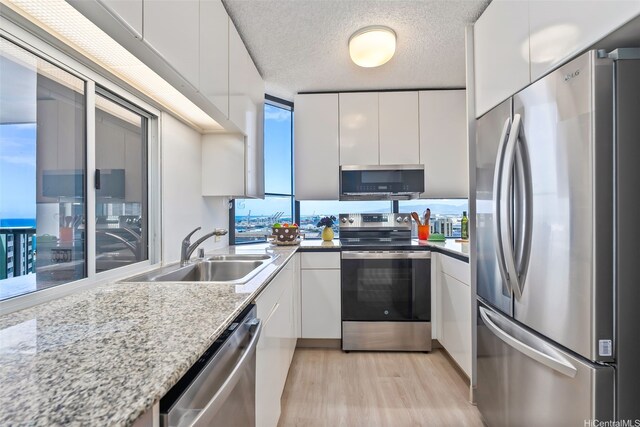 1212 Nuuanu Ave Unit 2509, Honolulu, HI 96817 - kitchen featuring stainless steel appliances, modern cabinets, light wood-type flooring, white cabinetry, and a textured ceiling