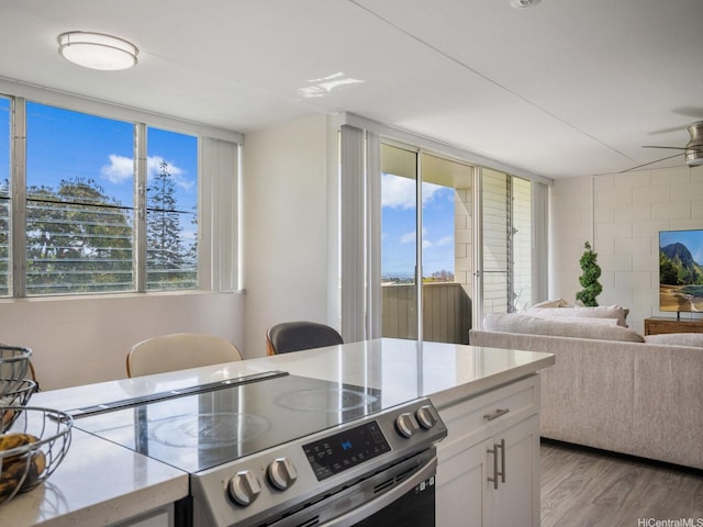 95-31 Kuahelani Ave Unit 439, Mililani, HI 96789 - kitchen featuring electric range, light wood-style floors, white cabinetry, ceiling fan, and open floor plan