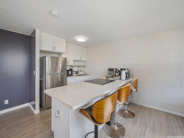 95-31 Kuahelani Ave Unit 439, Mililani, HI 96789 - kitchen with freestanding refrigerator, black electric stovetop, a sink, light wood-type flooring, and light countertops