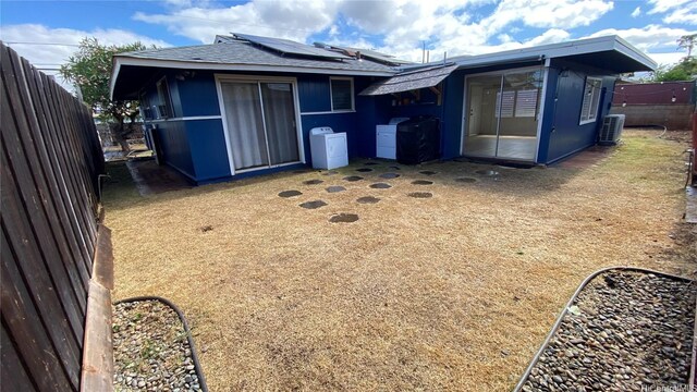 91-517 Pohakupuna Rd, Ewa Beach, HI 96706 - back of property featuring roof mounted solar panels, a fenced backyard, and roof with shingles