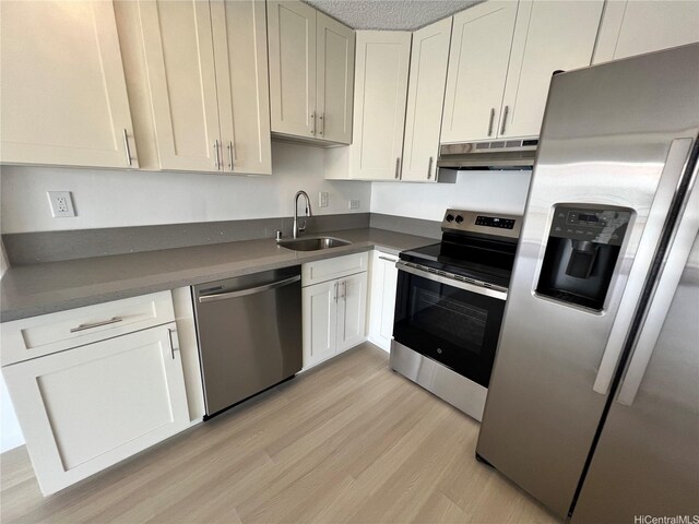 909 Ala Lilikoi St Unit 505, Honolulu, HI 96818 - kitchen featuring stainless steel appliances, under cabinet range hood, light wood-type flooring, white cabinets, and dark countertops