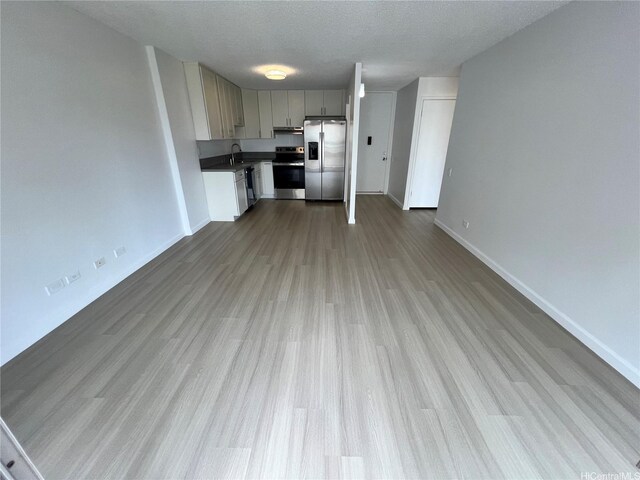 909 Ala Lilikoi St Unit 505, Honolulu, HI 96818 - kitchen featuring stainless steel appliances, wood finished floors, under cabinet range hood, a textured ceiling, and open floor plan