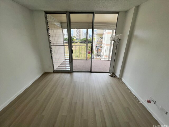 909 Ala Lilikoi St Unit 505, Honolulu, HI 96818 - empty room with floor to ceiling windows and wood finished floors