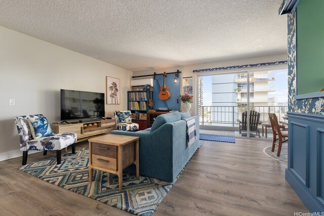 1111 Wilder Ave Unit 14B, Honolulu, HI 96822 - living room with a wall mounted AC, wood finished floors, and a textured ceiling
