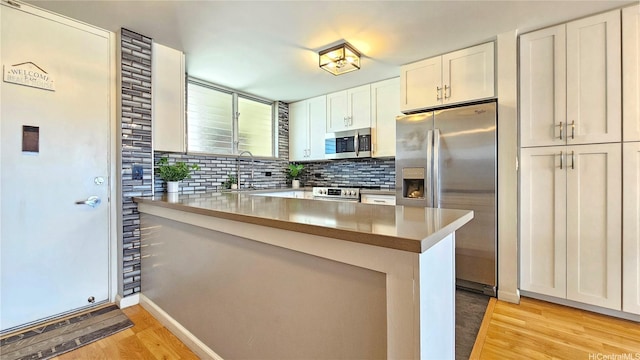 1717 Ala Wai Blvd Unit 2002, Honolulu, HI 96815 - kitchen featuring appliances with stainless steel finishes, light wood finished floors, a peninsula, decorative backsplash, and white cabinetry