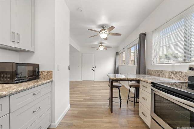 1447 Kewalo St Unit 101, Honolulu, HI 96822 - kitchen with stainless steel electric range oven, black microwave, a ceiling fan, and light wood-style flooring