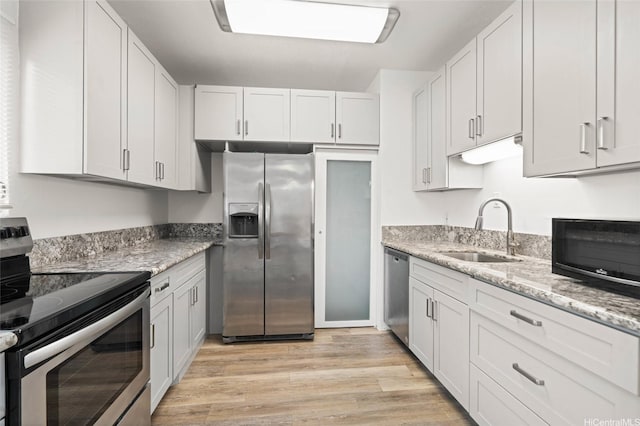 1447 Kewalo St Unit 101, Honolulu, HI 96822 - kitchen with appliances with stainless steel finishes, a sink, light wood finished floors, light stone countertops, and white cabinetry