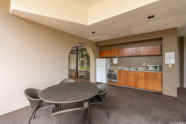 583 Kamoku St Unit Dh2303, Honolulu, HI 96826 - kitchen with appliances with stainless steel finishes, brown cabinetry, arched walkways, light countertops, and modern cabinets