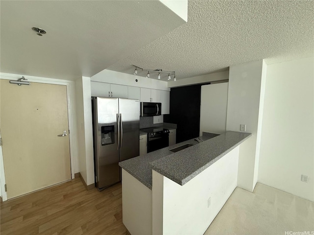215 N King St Unit 2205, Honolulu, HI 96817 - kitchen with stainless steel fridge, electric range, a textured ceiling, a peninsula, and a sink