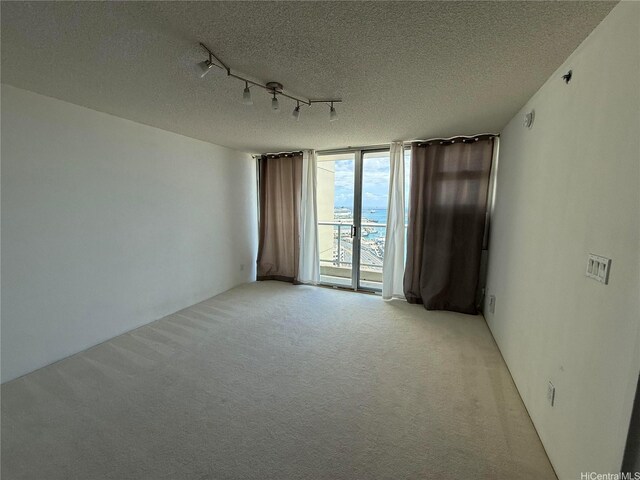215 N King St Unit 2205, Honolulu, HI 96817 - spare room with a wall of windows, a textured ceiling, light colored carpet, and track lighting
