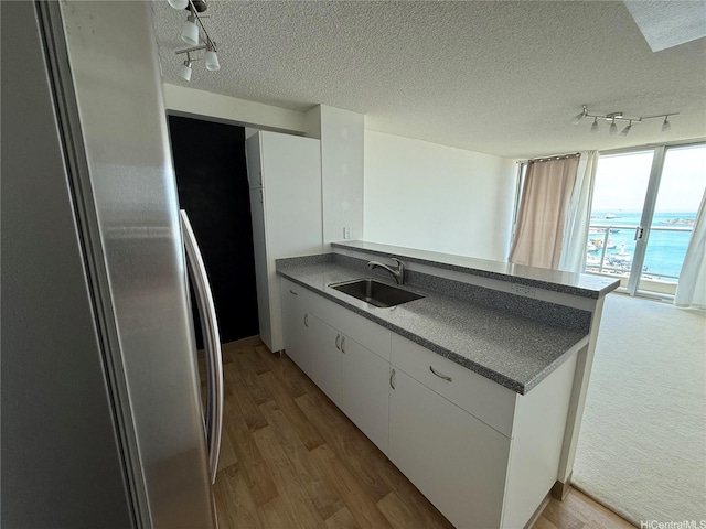 215 N King St Unit 2205, Honolulu, HI 96817 - kitchen with a sink, rail lighting, dark countertops, a peninsula, and light wood-style floors