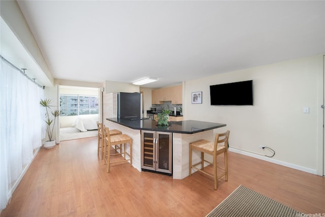2525 Date St Unit 405, Honolulu, HI 96826 - kitchen featuring beverage cooler, a kitchen bar, light wood-style flooring, dark countertops, and freestanding refrigerator