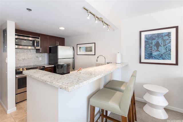 1777 Ala Moana Blvd Unit 2430, Honolulu, HI 96815 - kitchen with appliances with stainless steel finishes, tasteful backsplash, a peninsula, a kitchen bar, and dark brown cabinets