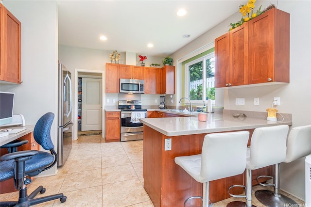 91-1152 Paapaana St, Ewa Beach, HI 96706 - kitchen with appliances with stainless steel finishes, light countertops, a peninsula, a kitchen bar, and a desk