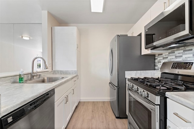 91-225 Hanapouli Cir Unit 33F, Ewa Beach, HI 96706 - kitchen with appliances with stainless steel finishes, white cabinetry, light wood finished floors, light countertops, and backsplash