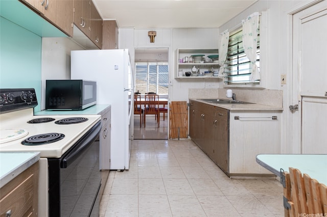 1968 10th Ave, Honolulu, HI 96816 - kitchen with electric range oven, black microwave, light countertops, a sink, and light tile patterned floors