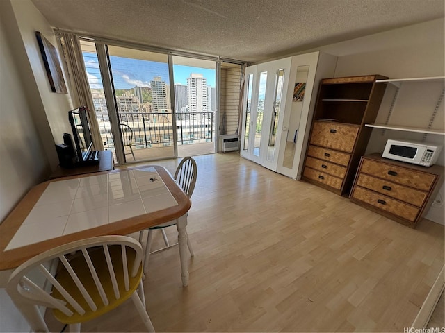 2345 Ala Wai Blvd Unit 2209, Honolulu, HI 96815 - dining space with floor to ceiling windows, wood finished floors, a textured ceiling, healthy amount of natural light, and an AC wall unit
