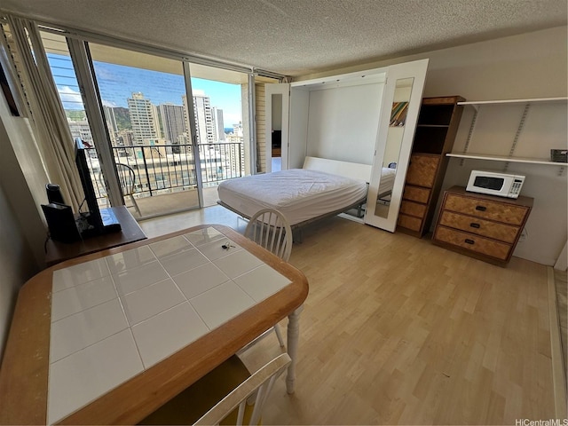 2345 Ala Wai Blvd Unit 2209, Honolulu, HI 96815 - bedroom with access to outside, wood finished floors, a textured ceiling, floor to ceiling windows, and a view of city