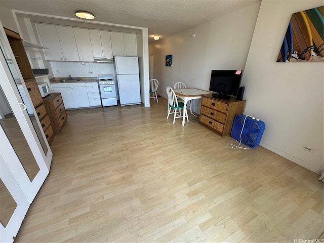 2345 Ala Wai Blvd Unit 2209, Honolulu, HI 96815 - kitchen with white appliances, light wood finished floors, white cabinets, a textured ceiling, and under cabinet range hood