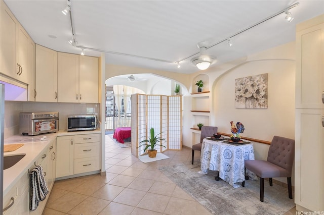 1020 Green St Unit 303, Honolulu, HI 96822 - kitchen featuring rail lighting, stainless steel microwave, arched walkways, light countertops, and light tile patterned floors