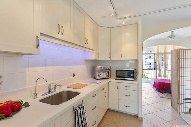 1020 Green St Unit 303, Honolulu, HI 96822 - kitchen featuring stainless steel microwave, light countertops, light tile patterned flooring, decorative backsplash, and arched walkways