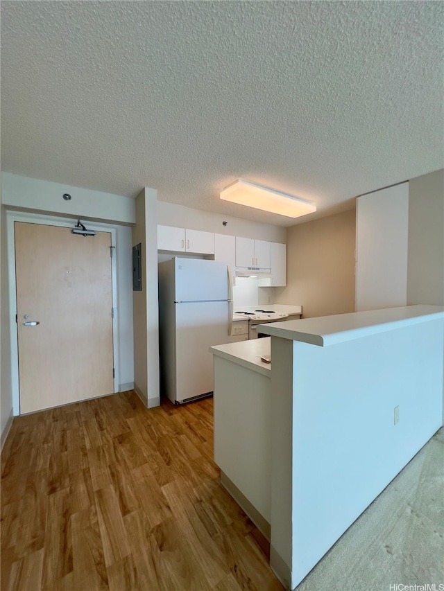 3009 Ala Makahala Pl Unit 1815, Honolulu, HI 96818 - kitchen with freestanding refrigerator, white cabinets, a textured ceiling, light countertops, and light wood-type flooring