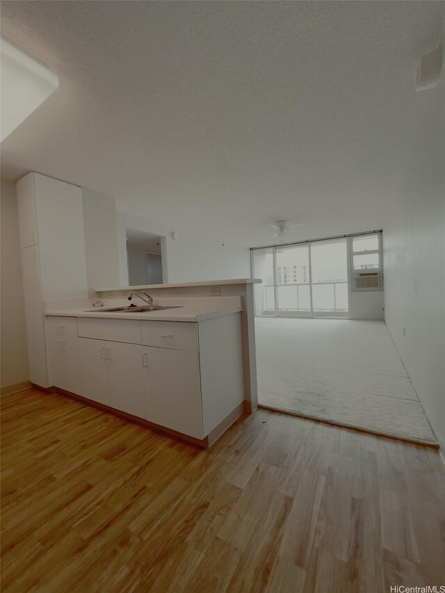 3009 Ala Makahala Pl Unit 1815, Honolulu, HI 96818 - kitchen featuring light wood-style flooring, white cabinets, light countertops, and cooling unit