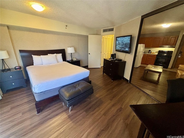 1088 Bishop Sts Unit 3109, Honolulu, HI 96813 - bedroom with freestanding refrigerator, dark wood finished floors, and a textured ceiling