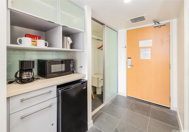 410 Atkinson Dr Unit 2418, Honolulu, HI 96814 - kitchen with black microwave, light countertops, dark tile patterned floors, open shelves, and baseboards