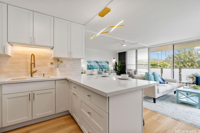53-549 Kamehameha Hwy Unit 402, Hauula, HI 96717 - kitchen featuring open floor plan, decorative backsplash, a ceiling fan, light wood finished floors, and a wall of windows