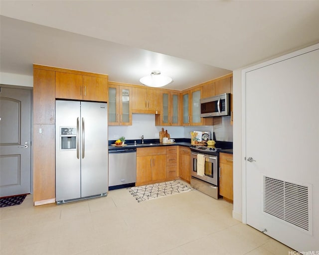 1009 Kapiolani Blvd Unit 2404, Honolulu, HI 96814 - kitchen with stainless steel appliances, dark countertops, glass insert cabinets, brown cabinetry, and a sink