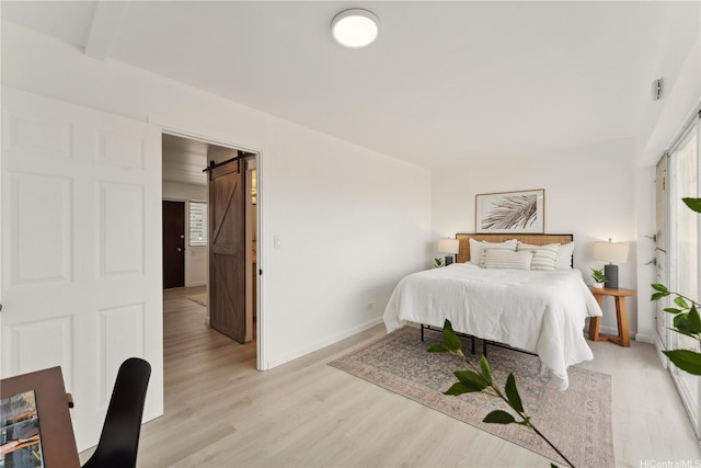 1620 Keeaumoku St Unit 506, Honolulu, HI 96822 - bedroom featuring a barn door, light wood-type flooring, and baseboards