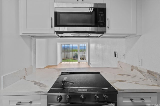 94-100 Huki Pl Unit S106, Waipahu, HI 96797 - kitchen featuring stainless steel microwave, black / electric stove, white cabinetry, and light stone countertops
