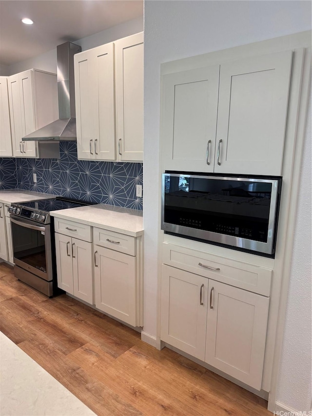 2318 Waiomao Rd Unit 4, Honolulu, HI 96816 - kitchen with wall chimney range hood, appliances with stainless steel finishes, light wood-type flooring, decorative backsplash, and recessed lighting