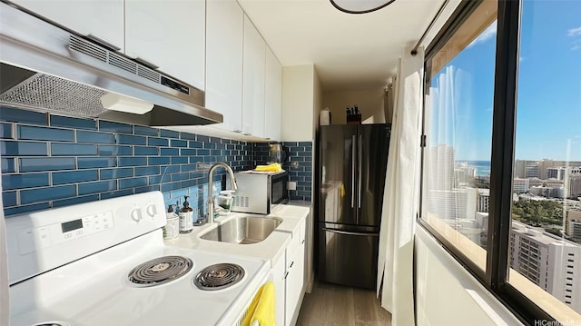 444 Niu St Unit 3802, Honolulu, HI 96815 - kitchen with white range with electric cooktop, freestanding refrigerator, under cabinet range hood, white cabinets, and plenty of natural light