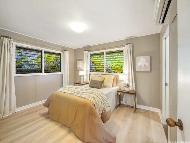 2527 Henry St Unit A, Honolulu, HI 96817 - bedroom featuring light wood-style flooring, a wall mounted air conditioner, and multiple windows