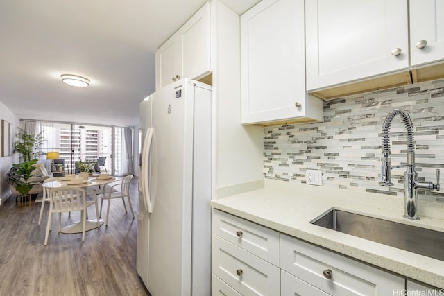 469 Ena Rd Unit 2004, Honolulu, HI 96815 - kitchen with freestanding refrigerator, a sink, wood finished floors, tasteful backsplash, and white cabinetry