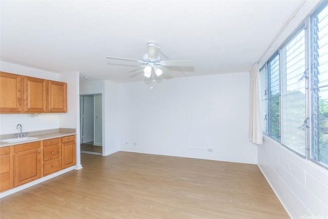 1550 Wilder Ave Unit A202, Honolulu, HI 96822 - kitchen with a sink, light countertops, light wood-style floors, ceiling fan, and brown cabinetry