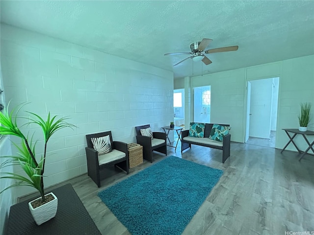 94-245 Leowahine St Unit D1005, Waipahu, HI 96797 - living area featuring concrete block wall, wood finished floors, a textured ceiling, and a ceiling fan