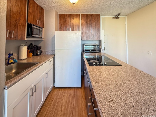 445 Seaside Ave Unit 1120, Honolulu, HI 96815 - kitchen featuring freestanding refrigerator, black electric stovetop, a sink, stainless steel microwave, and a textured ceiling